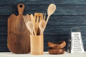 closeup shot of cutting board, kitchen utensils, grater and ramekins in front of wooden wall