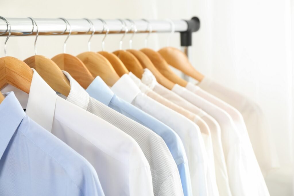 Hangers with shirts against light background, close up