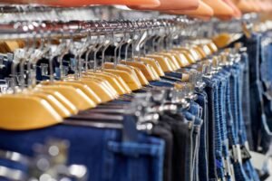 Many denim jeans hanging on wooden hangers, shopping concept