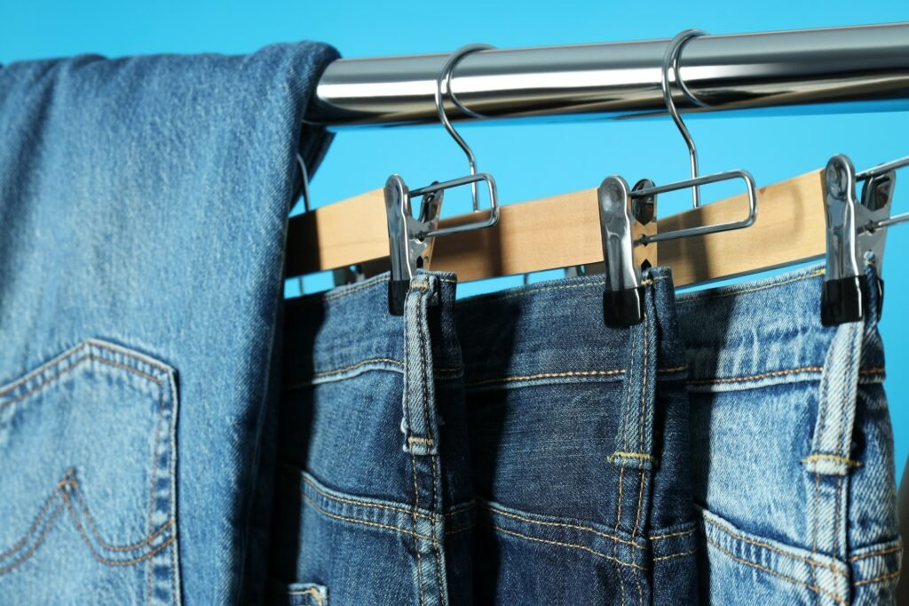 Ukraine, Kyiv, 28.10.2023 Jeans hang on hangers on a blue background